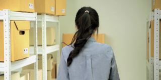 亚洲女工在仓库分拣箱子到仓库货架，储存和分配的概念。