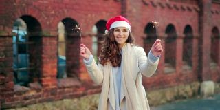 幸福的年轻女人的肖像，穿着大衣，戴着圣诞老人的圣诞帽，手里拿着烟花