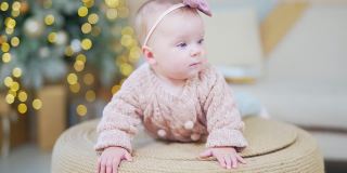 6个月大的可爱宝宝的特写照片。孩子的脸，头上戴着蝴蝶结，头上织着毛衣