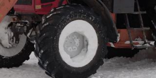 冬天，一辆带着黄色铲斗的拖拉机在街上铲雪。道路清洁援助，工业。缓慢的莫
