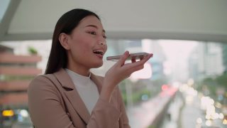年轻的亚洲女人使用语音信息聊天移动电话移动电话视频素材模板下载