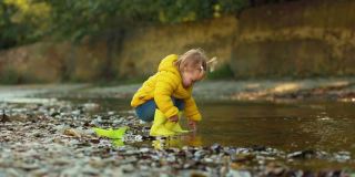 一个穿着胶靴的可爱小女孩在河边玩耍。慢动作