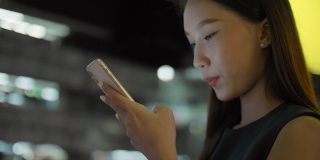 年轻的亚洲女人在晚上用手机