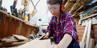年轻貌美的30-40岁的职业女木匠，在木工diy车间用砂纸打磨原木。