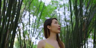 快乐的亚洲女人走在美丽的竹林下。女性旅游生态旅游