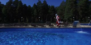 快乐的圣诞老人在游泳池边跳舞