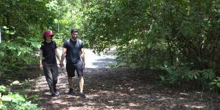 一对快乐的年轻夫妇一起走过自然公园的森林。年轻的男女朋友徒步旅行在林地