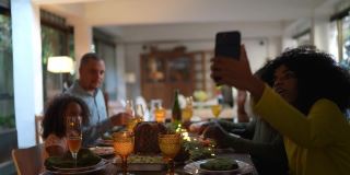 一名年轻女子和她的家人在家里吃圣诞晚餐时用智能手机视频通话