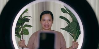 亚洲女性在家卖植物，用智能手机直播的特写镜头