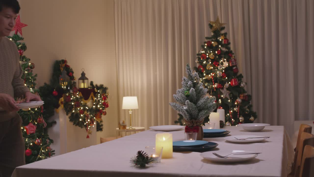 亚洲单身男子今晚准备圣诞夜餐桌布置派对。