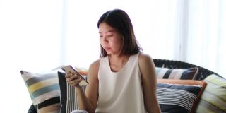 亚洲女人放松玩智能手机在客厅