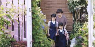 一位亚洲华裔母亲早上把她的两个女儿送到她家的前院上学