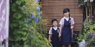 早上，亚洲的中国姐妹们手牵着手从家走到房子的前院上学