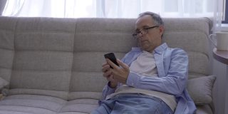 50-60岁的老人微笑着看着智能手机屏幕。