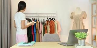 亚洲女企业家注意并检查库存的服装产品在网上服装商店