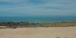 周末度假时，亚洲美女用相机在海边的沙滩上拍照。快乐单人旅行的概念。4 k慢动作。