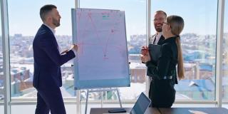 愉快的商务人士在办公室交谈。规划新战略的经理团队合作。一群企业家在黑板旁边用图表谈论生意。