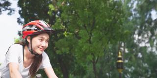亚洲年轻美女在公园骑车养生。活跃的运动员运动女孩在运动服感觉清新和放松，通过骑自行车锻炼，在晚上的保健和健康