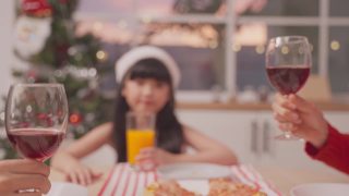 亚洲可爱的家庭成员在家里一起庆祝圣诞派对。漂亮迷人的父母在餐桌上碰杯，吃着传统的庆祝晚餐。视频素材模板下载