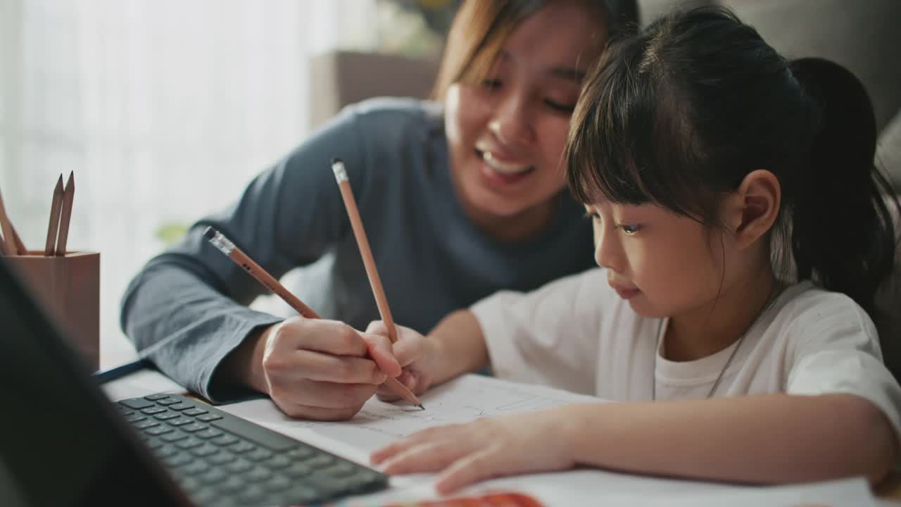 母亲帮助女儿使用笔记本电脑进行家庭教育