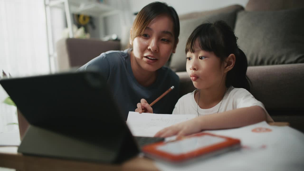母亲帮助女儿使用笔记本电脑进行家庭教育