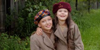 可爱快乐的小女孩们戴着贝雷帽在户外拥抱