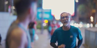 一名亚裔中国男子鼓励他的父亲晚上下班后一起在城市里慢跑