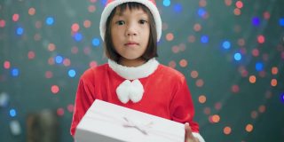 女孩穿着圣诞老人的衣服打开礼品盒。