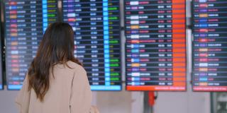 旅客在机场戴着口罩看航班时刻表。