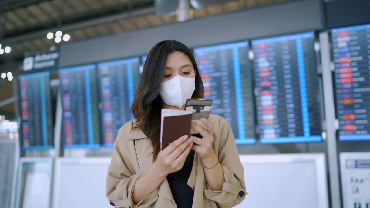 一名女乘客在机场戴着口罩发短信。