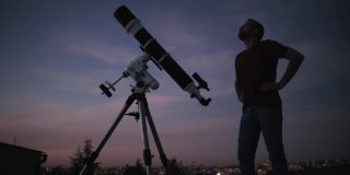 一个人的剪影，望远镜和星空下的乡村。