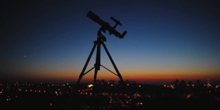 望远镜的轮廓和遥远的城市地平线。