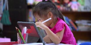 在线教育的概念。在线课堂。亚洲小女孩在家学习。孩子在家里的客厅里用数码平板画画。
