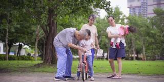 亚洲的祖父母教孙子骑自行车，与家人一起散步和锻炼