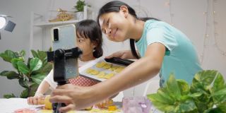 亚洲女孩拍摄她姐姐在家做饭的视频，为病毒视频或TikTok在家，新一代的时尚生活理念。