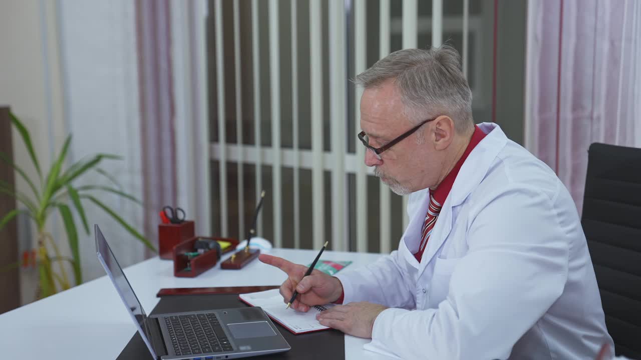 医院远程会诊。家庭治疗师通过笔记本电脑与病人交谈。医生在网上和病人聊天，并在笔记本上写东西。