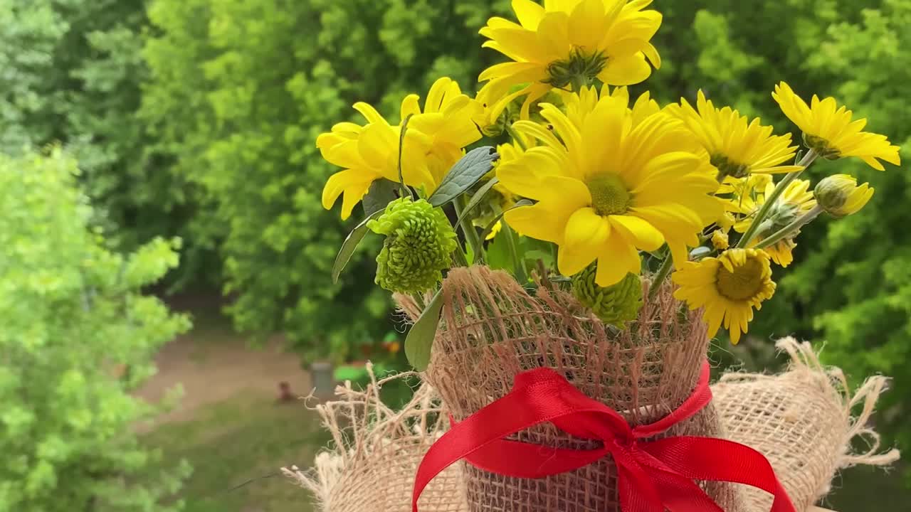 阳台木桌上有一束黄色的花。夏天绿色自然背景