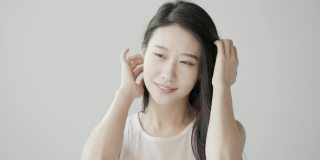 黑色长发的韩国美女在白色摄影棚里拍照。风吹过她的头发。慢动作视频