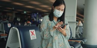 女旅客在机场候机时使用手机。