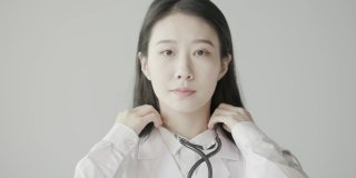 年轻美丽的亚洲女医生，带着自信的微笑看着镜头，一个成功的医生形象