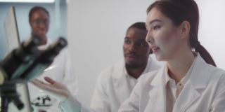 多元化的团队在现代化的实验室中工作。女人和男人在研究过程中讨论