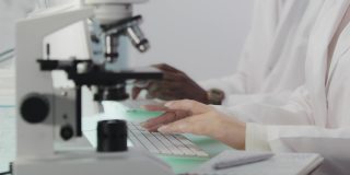 非洲和亚洲的科学家正在研究DNA样本。电脑屏幕和显微镜。近距离做笔记