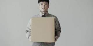 年轻的亚洲快递员穿着快递公司的制服，把快递箱递给了顾客