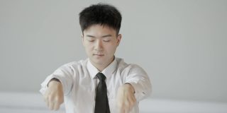 年轻的亚洲男性白领在办公室里锻炼身体。简单的办公室运动有助于恢复精力
