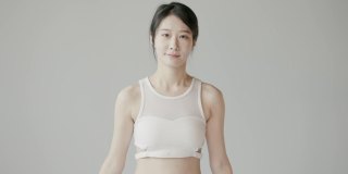 可爱的韩国女性跳绳在白色的工作室，穿着紧身裤和运动背心，精力充沛健康的女性