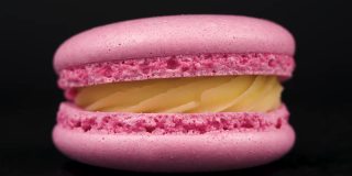 粉红色马卡龙旋转在黑色背景。食品的概念。糖果在唱机转盘上靠近