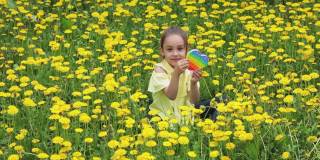 女孩手里拿着一个五颜六色的心形爆笑游戏，然后按下泡泡。流行的流行玩具彩虹颜色的特写