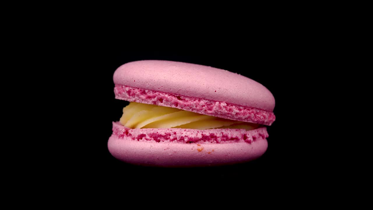 在黑色背景上旋转的粉色马卡龙。食品的概念。糖果关闭在一个转盘