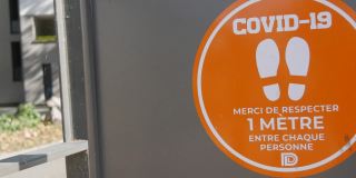 铭文是用法语写的。由于COVID-19，电车车站的距离警告标志
