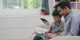 亚洲家庭父母和儿子使用笔记本电脑申请应用手表家庭娱乐。假日家庭度假与家庭科技
